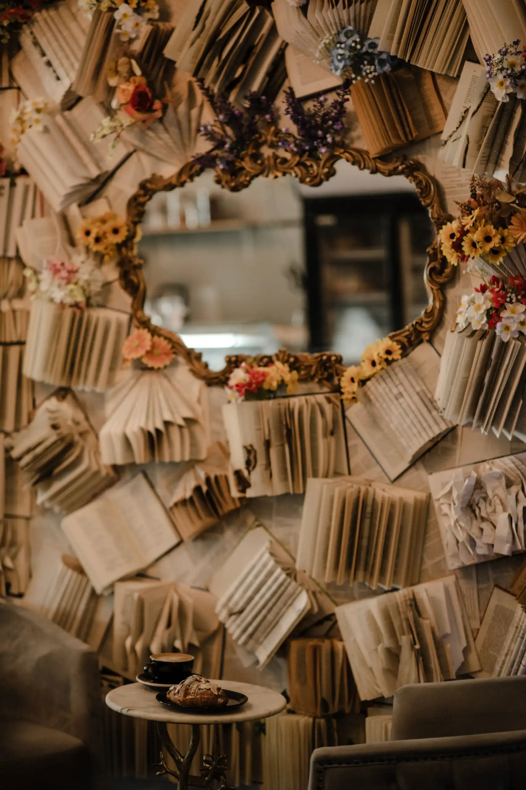 An ornate mirror on a wall of folded book pages