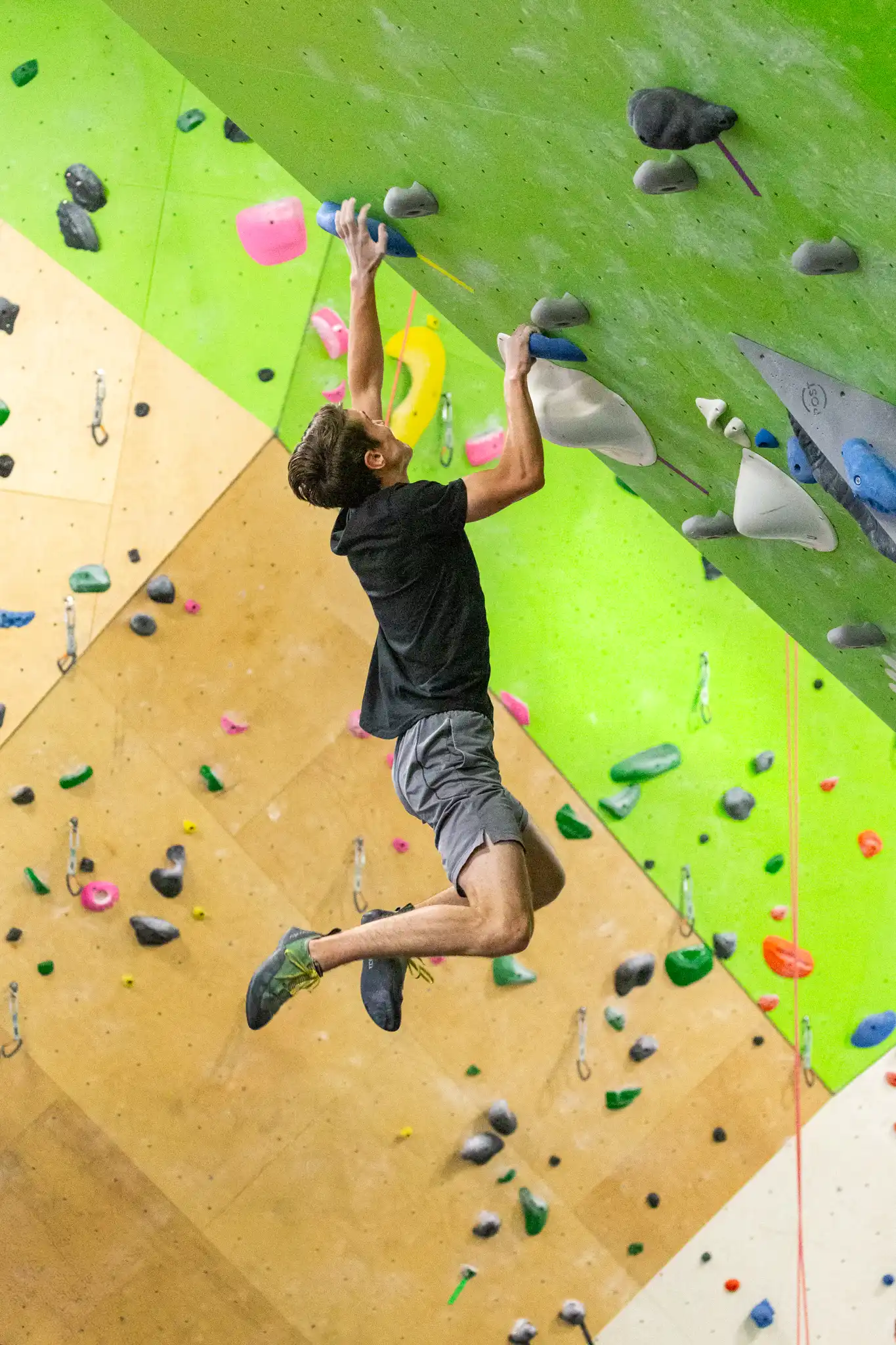 A climber reaching for a hold on an indoor bouldering wall